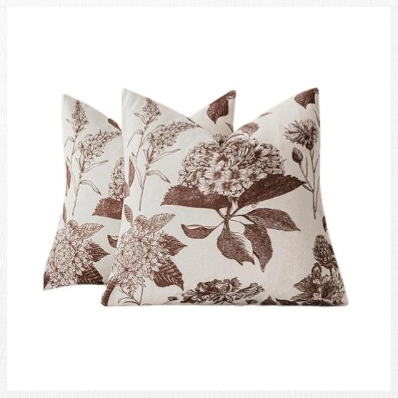 Two decorative throw pillows with a cream background and brown floral prints, featuring detailed images of flowers and leaves, make perfect fall decor finds, displayed against a plain white background.