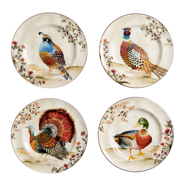 A set of four decorative plates, each featuring a different bird in a naturalistic setting with floral accents. The birds include a quail, a pheasant, a turkey, and a mallard duck. The plates have a vintage, hand-painted appearance with intricate details and earthy tones.