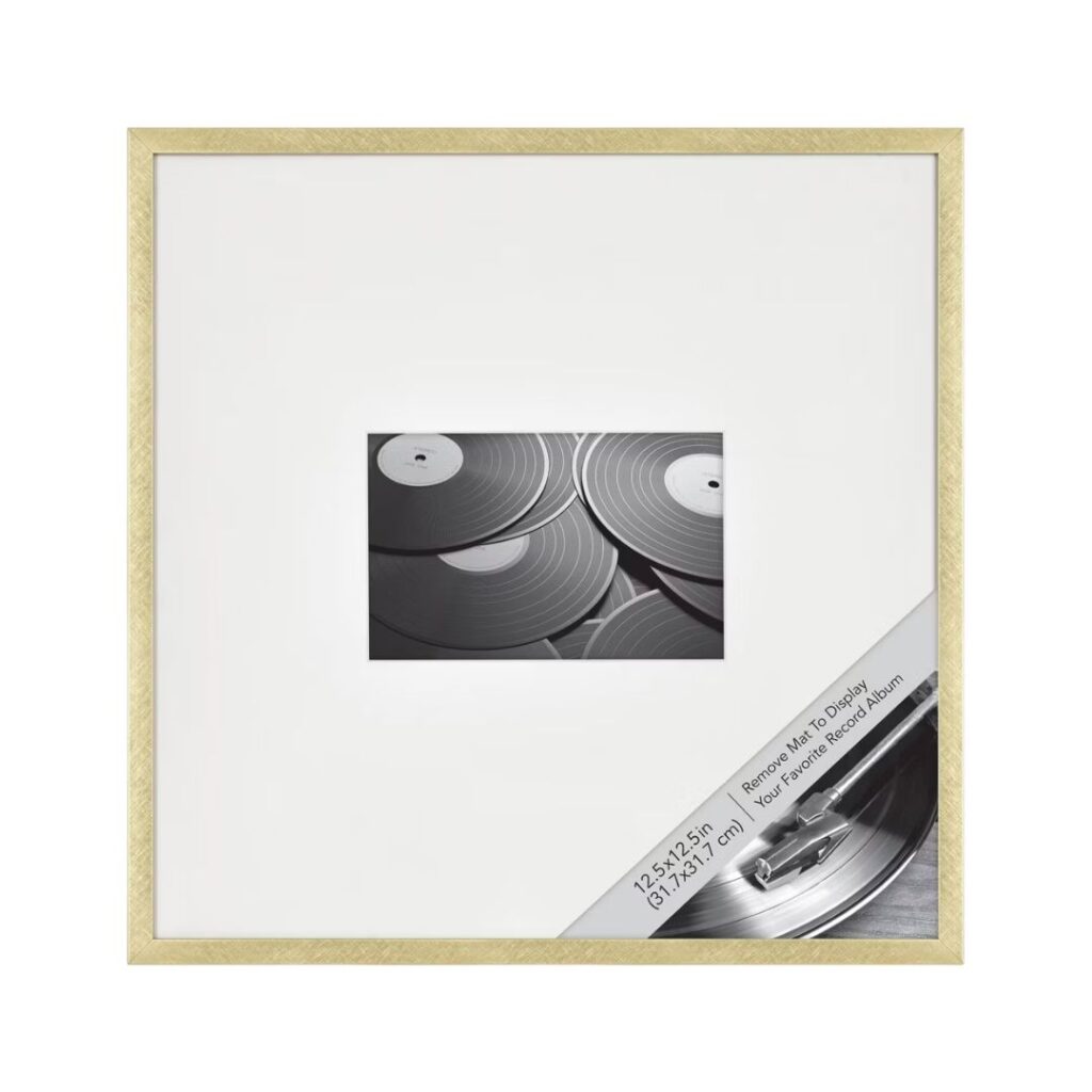 A square wooden picture frame with a white mat showcases a black and white photograph of several vinyl records. A corner insert displays text about the frame's dimensions: 12x12 inches or 31x31 centimeters, along with product care information—perfect for a quick Rub 'n Buff picture frame makeover.