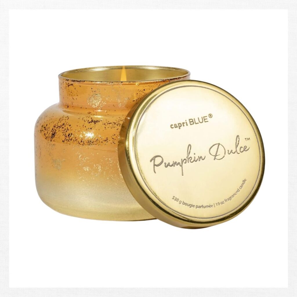 A gold, speckled glass candle jar with a matching lid labeled "capri BLUE Pumpkin Dulce," perfect for fall kitchen decor ideas on a budget. The lid rests beside the open jar, revealing the candle inside.