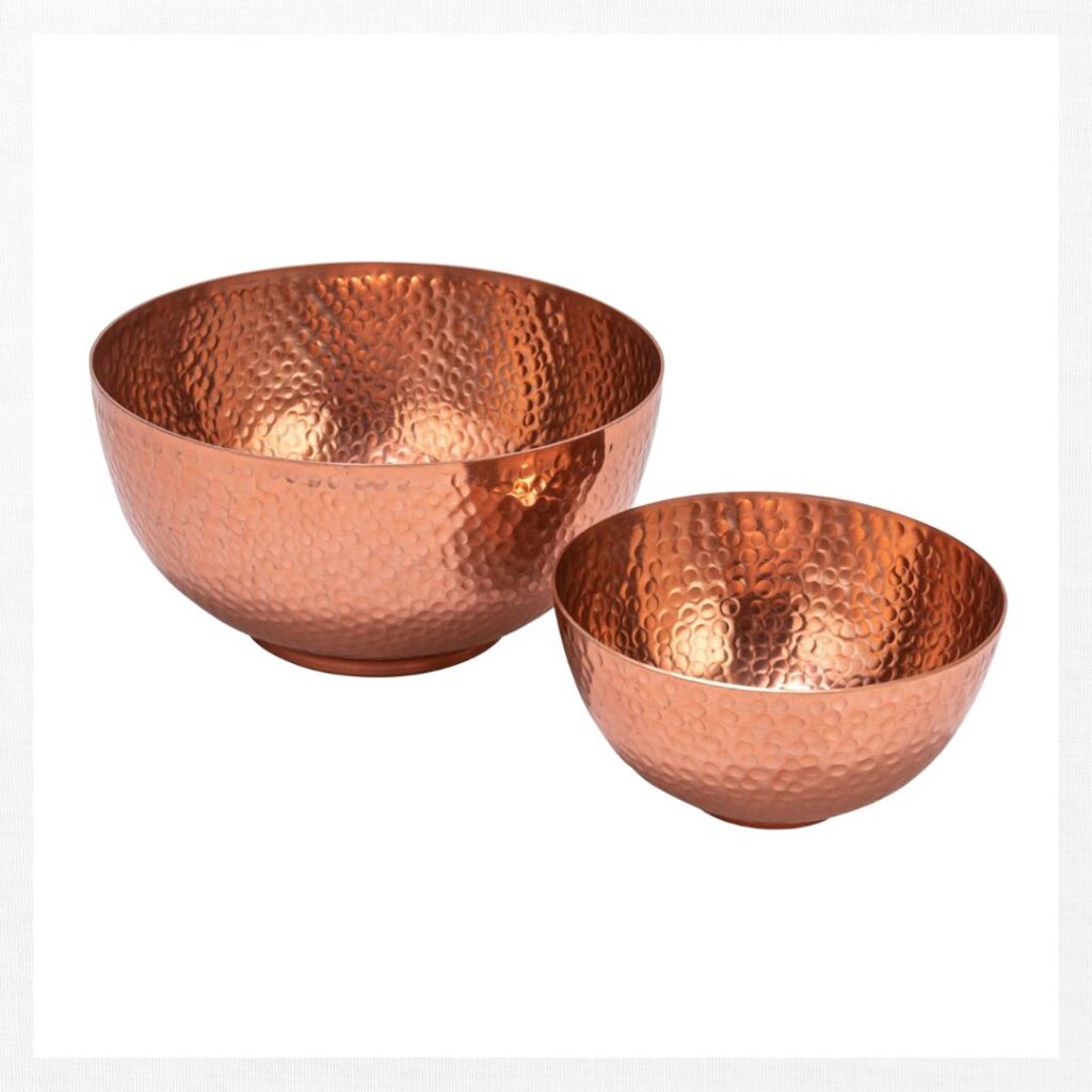 Two hammered copper bowls, one larger and one smaller, are placed side by side on a plain white background—perfect inspiration for fall kitchen decor ideas on a budget.