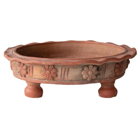 A round, shallow terracotta planter with three short legs and decorative flower patterns around the sides. Perfect for those seeking ideas on how to decorate a footed bowl, its wavy rim and textured surface create a charming rustic look.