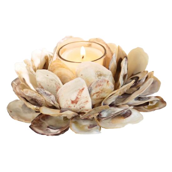 A lit tealight candle is held in a glass holder, surrounded by layers of natural seashells arranged to resemble a blooming flower—a creative idea for how to decorate a footed bowl with coastal charm.