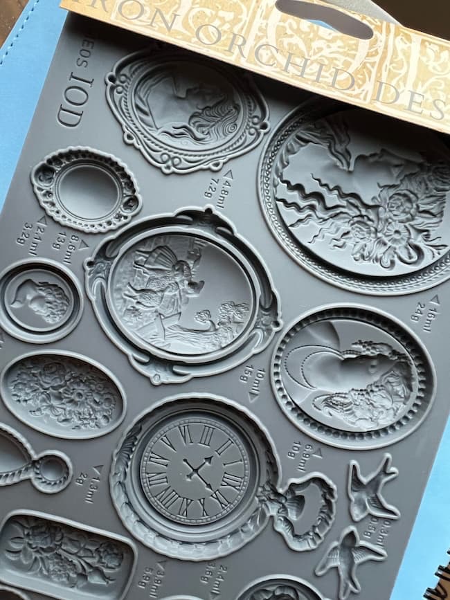 A silicone mold tray featuring various ornate designs, including vintage-style picture frames, a clock face with Roman numerals, and decorative bird and floral motifs—perfect for adding a Cozy Start to your creative projects.