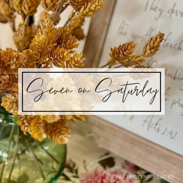 A close-up of a vase with dried golden flowers next to a framed sign. Overlaid text reads "Seven on Saturday" in cursive script, offering Fresh Inspiration for October. The bottom right corner says "Perfecting Places.