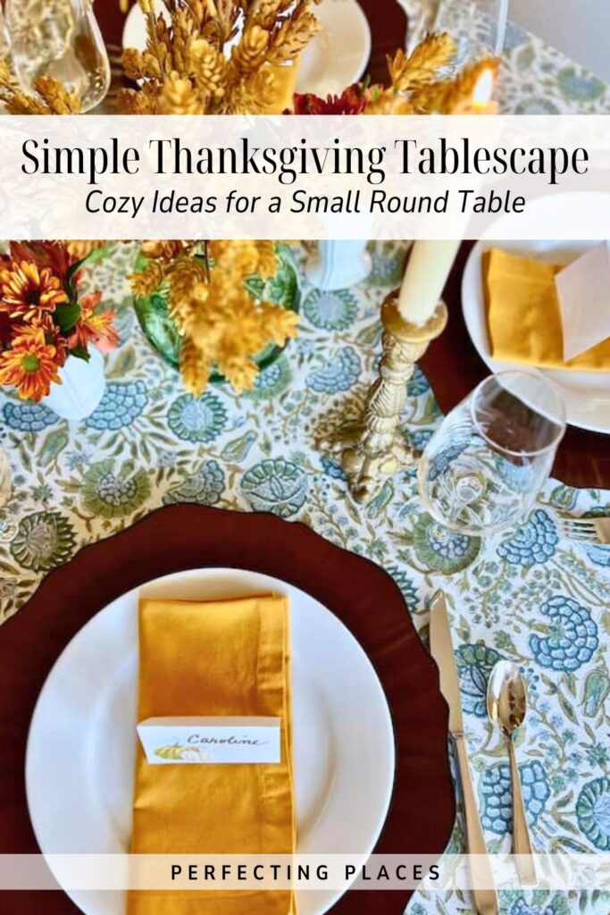 A small table set for Thanksgiving with a floral tablecloth, white plates, gold flatware, yellow napkins, candles, and fall flowers. A name card labeled “Caroline” rests on a plate. Text overlay highlights Thanksgiving tablescape ideas and fall style.